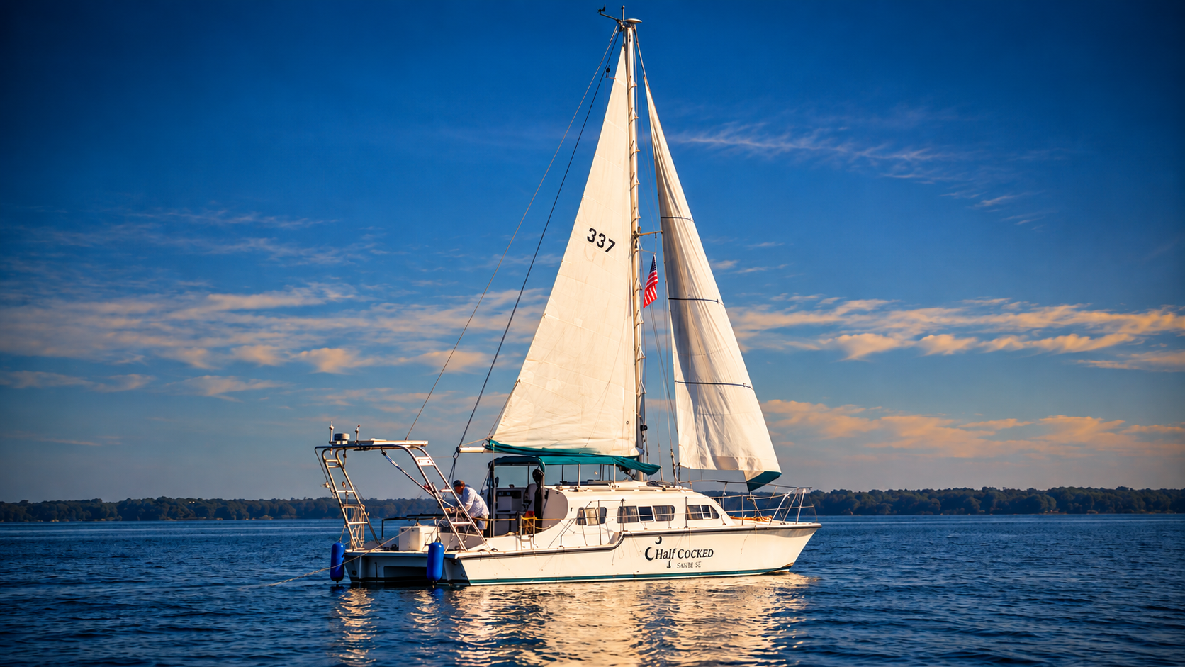 Half Cocked under sail, with his full mast and white sails above the water.